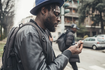 portrait of young african man standing in the street and smoking cigar