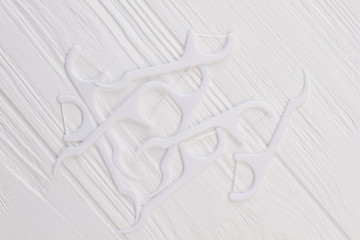 Dental floss toothpick on white wooden background. Tools for teeth cleaning. Concept of oral...