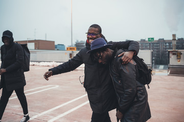 three young african men outdoor together hugging having fun