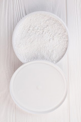 Powder for teeth cleaning, top view. Jar with powder for teeth cleaning on white wooden background.