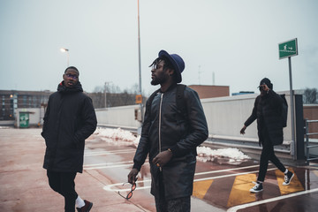 three young african men walking in the street and speaking