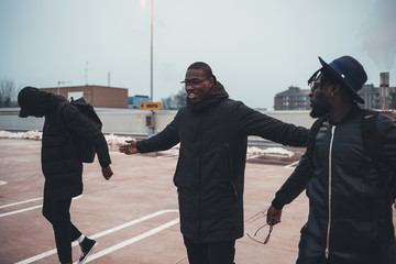 three young african men walking in the street and speaking