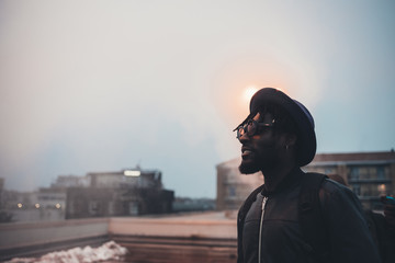 portrait of young african man standing on terrace and looking horizon