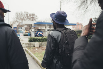 Back view three young african men walking in the street together