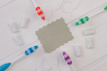 Different tools for dental care on white background. Toothbrushes, dental floss and blank paper...