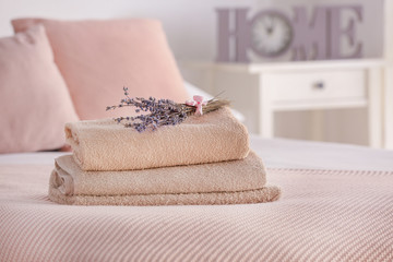 Stack of clean towels with lavender flowers on bed