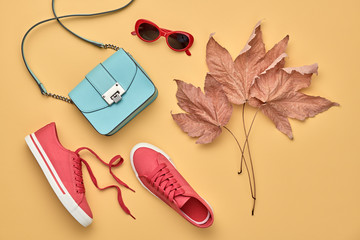 Fall fashion Accessories set. Autumn mood, creative minimal Flat lay. Trendy Sunglasses, Stylish red sneakers, glamour handbag, fashionable look. Autumnal color, shopping concept. Maple Leaf
