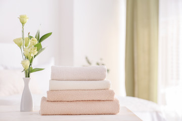 Fototapeta na wymiar Stack of clean towels on table in bedroom