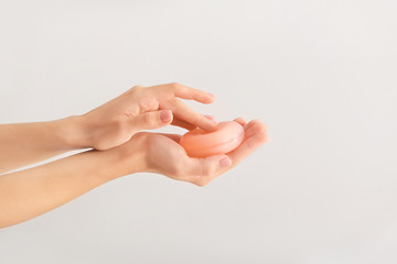 Female hands with soap bar on light background