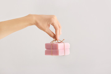 Female hand with soap bars on light background