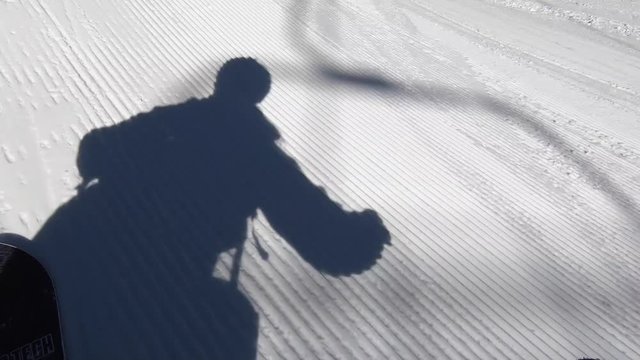 Shadow of snowboarder doing grabs over jumps