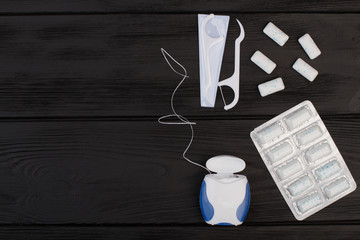 Chewing gums and dental floss on dark background. Teeth cleaning concept with copy space.