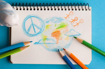 Notepad with color pencils and child drawing