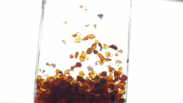 pieces of amber in water falling to the bottom slow motion