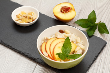 Sorghum salad with nuts and fresh peach on stone board.