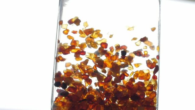 pieces of amber in water falling to the bottom slow motion