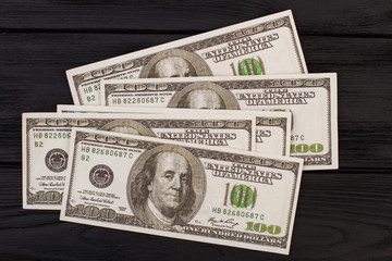 Four hundred American dollars on dark background. USA dollars banknotes on black wooden surface.