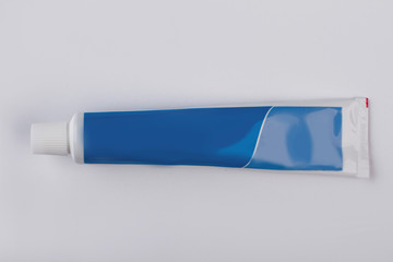 Blue tube of toothpaste on light background. Plastic tube of toothpaste, horizontal image.