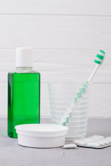 Set of tools for oral hygiene. Mouthwash bottle, glass with toothbrush, powder for teeth cleaning and chewing gums. Dental care concept.