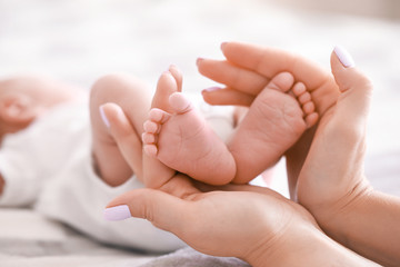 Obraz na płótnie Canvas Mother's hands with tiny baby legs, closeup
