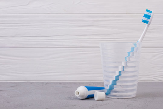 Toothbrush and toothpaste on wooden background. Glass with toothbrush in barthroom. Space for text.