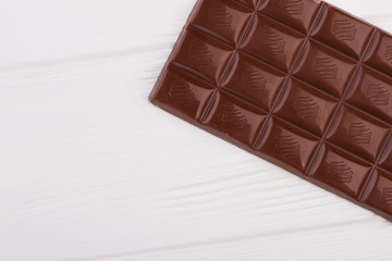 Bar of milk chocolate and copy space. Gluten free chocolate bar on white wooden background. Concept of healthy sweets.