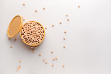 Container with raw chickpea on light background