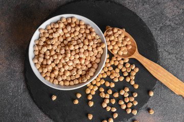 Bowl with raw chickpea and spoon on table