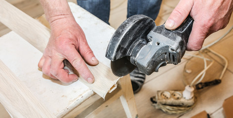 Man is cutting baseboard. Repair works indoors. Renovation in the flat.  Angle grinder in hands.