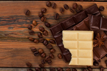 Chocolate bars and coffee beans on wooden background. Chocolate pieces and coffee beans on rustic wooden surface.