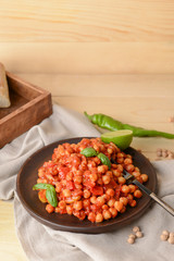 Plate with tasty chickpea in tomato sauce on table