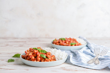 Plate with tasty chickpea in tomato sauce and boiled rice on table