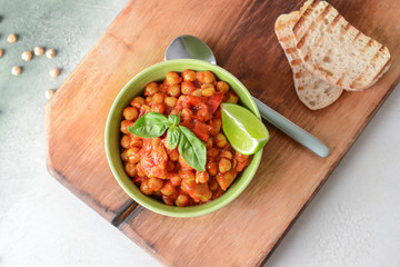 Bowl with tasty chickpea in tomato sauce on table