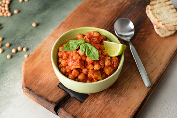 Bowl with tasty chickpea in tomato sauce on table