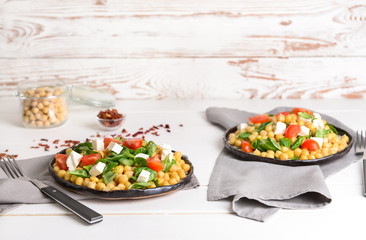 Plates with tasty chickpea salad on table