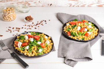 Plates with tasty chickpea salad on table