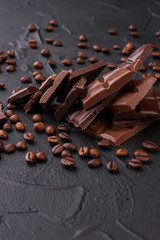 Chocolate and coffee beans on black concrete background. Dark chocolate pieces and coffee beans. Taste of perfection.