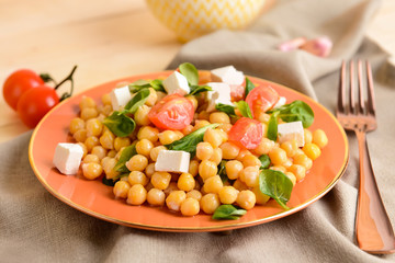 Plate with tasty chickpea salad on table