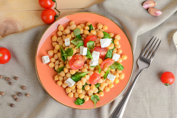 Plate with tasty chickpea salad on table