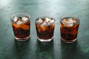 Glasses of cold cola on color table