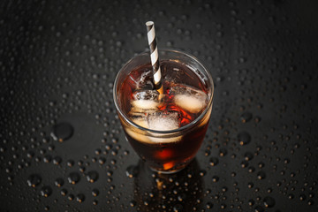Glass of cold cola on dark table