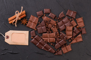 Heart shape made of chocolate and coffee beans. Shape of heart from chocolate pieces, cinnamon sticks and blank price tag.
