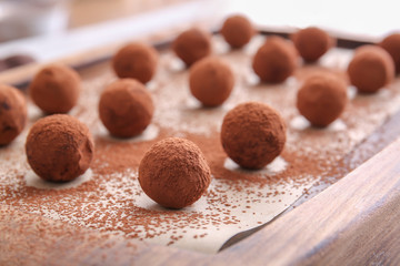 Tasty sweet truffles with cacao powder on board, closeup
