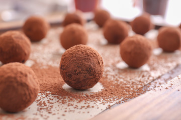 Tasty sweet truffles with cacao powder on board, closeup