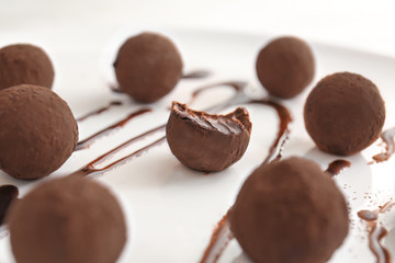 Tasty sweet truffles with chocolate sauce on plate, closeup