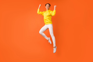 Fototapeta na wymiar Full length photo of cheerful person raising fists screaming yes jumping isolated over orange background