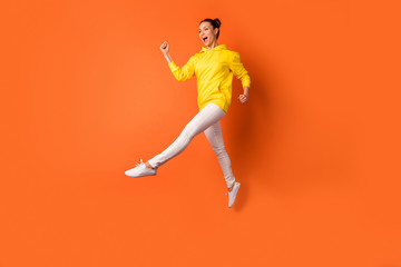 Fototapeta na wymiar Full size photo of cute childish person moving raising legs wearing white pants trousers isolated over orange background