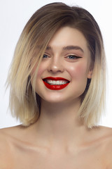 Close-up portrait of a beautiful woman smiling at the camera. Short hair and evening makeup. Red lips and eyeliner. Happy smile with white teeth. Spa and cosmetology, dentistry