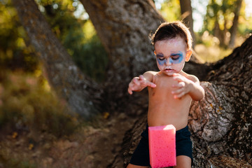 Kid painting himself of dracula to halloween on the forest