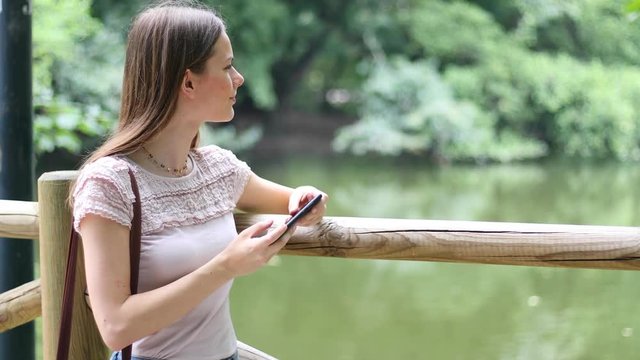 Young woman using her smartphone outdoor in a park and taking pictures
